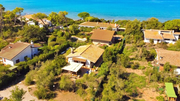 Un quartier résidentiel situé sur la côte, avec des maisons, dont certaines sont dotées de toits en tuiles, entouré de verdure et offrant une vue sur la mer.