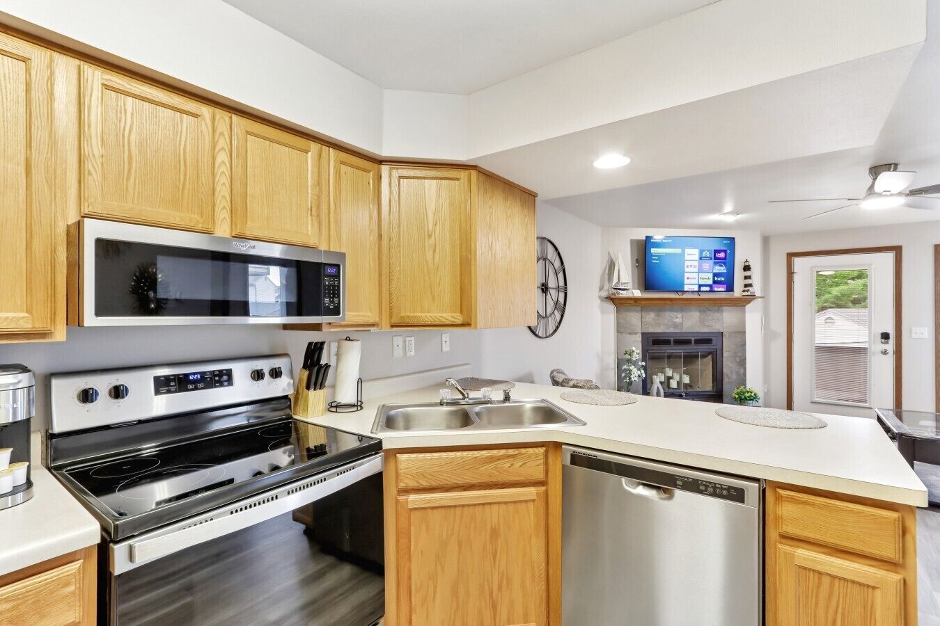 A modern kitchen with wooden cabinets, stainless steel appliances, a built-in microwave, and a dishwasher.