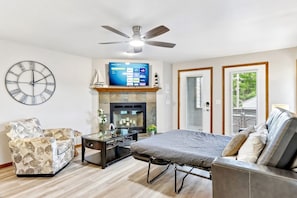 A living room with a sofa, armchair, TV, fireplace, and ceiling fan. - Ground Floor at Lighthouse Cove (Wisconsin Dells)