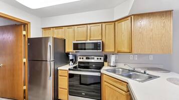 A modern kitchen with stainless steel appliances, wooden cabinets, and a white countertop.