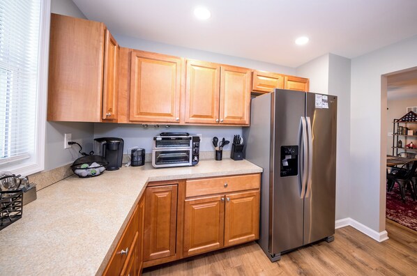 Una cocina con armarios de madera, un refrigerador de acero inoxidable, un tostador y una cafetera.