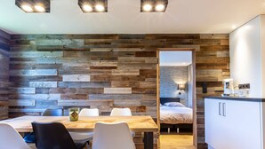 Une cuisine moderne avec un mur en bois, un coin repas avec des chaises et un lit dans la pièce adjacente.