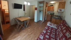 Een compacte woonruimte met een eethoek, kitchenette en een slaapbank.