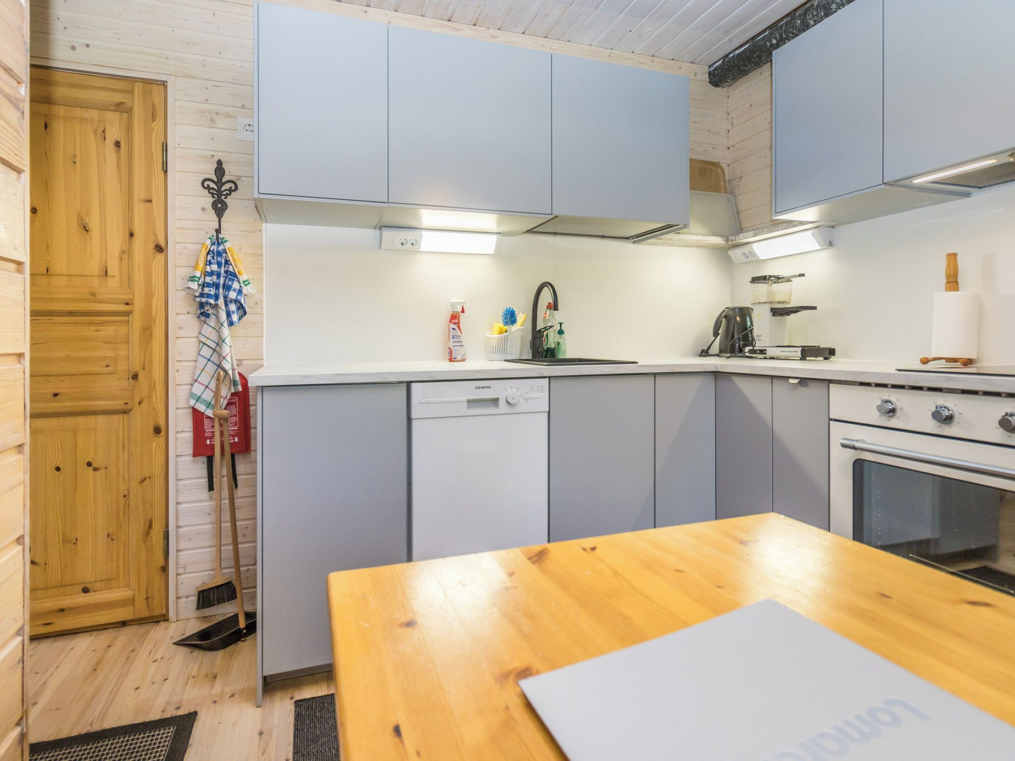 Une cuisine compacte équipée d’un lave-vaisselle, d’une cuisinière et d’une table en bois.