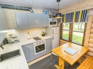 Et lille køkken med indbygget ovn, et spisebord og et vindue med udsigt til det fri.