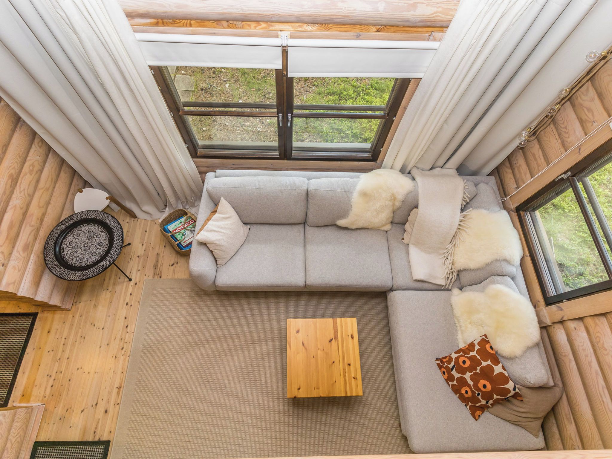 Een knus interieur met een bank, een tafeltje en een raam met uitzicht op groen.