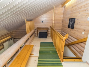 Et træinteriør med skråvægge, en bænk, et bord og en pejs.
