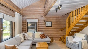 A cozy log cabin interior with a wooden staircase, a sectional sofa, and a wooden coffee table. - Kiilopään tunturimajat b6 / kerttula by Interhome (Inari)