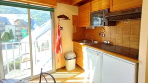 Une cuisine avec des meubles de rangement en bois, un four à micro-ondes, un évier et une poubelle.