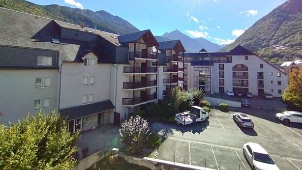 Un hôtel à plusieurs étages doté de balcons, d’un parking et surplombant des montagnes.