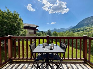 A balcony with a table and chairs, overlooking a mountainous landscape. - Cozy apartment at the foot of the slopes with pool (Flumet)