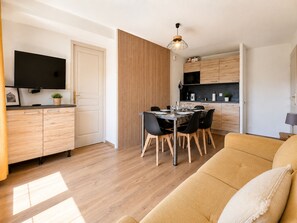 Una sala moderna con sofá, mesa de comedor y zona de cocina.