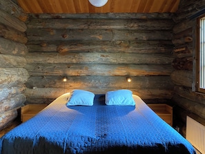A log cabin bedroom with a bed, two pillows, and a quilt.