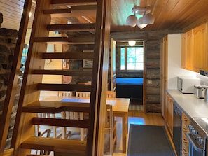 A wooden interior with a staircase, a dining area, and a kitchen with modern appliances.