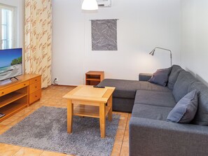 En stue med sofa, sofabord, fjernsyn og lampe.