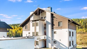 Een modern meerlaags gebouw met een schuin dak, een zichtbaar balkon en een klein terras.
