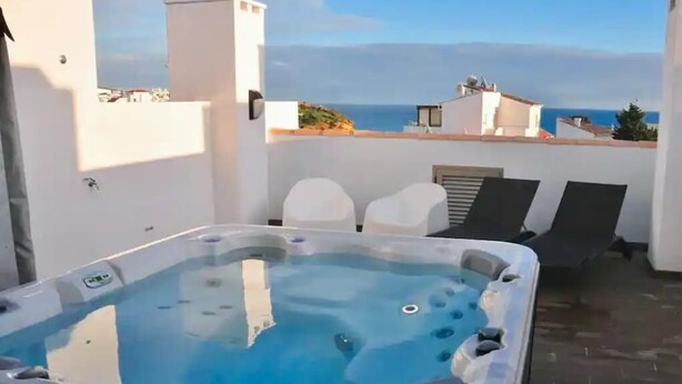 A hot tub on a rooftop terrace with a view of the sea.