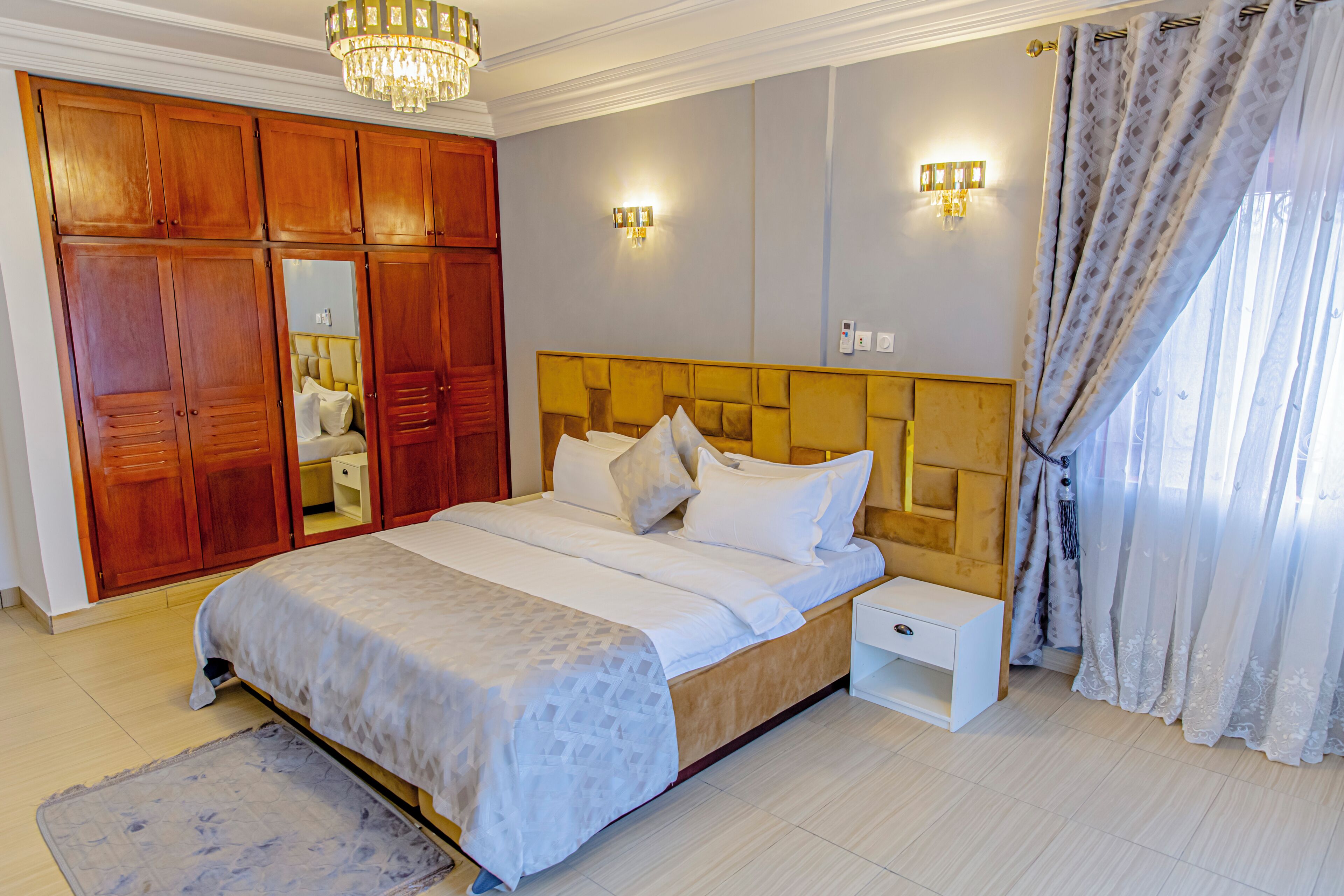 Un dormitorio con cama, armario de madera, mesita de noche y candelabro.