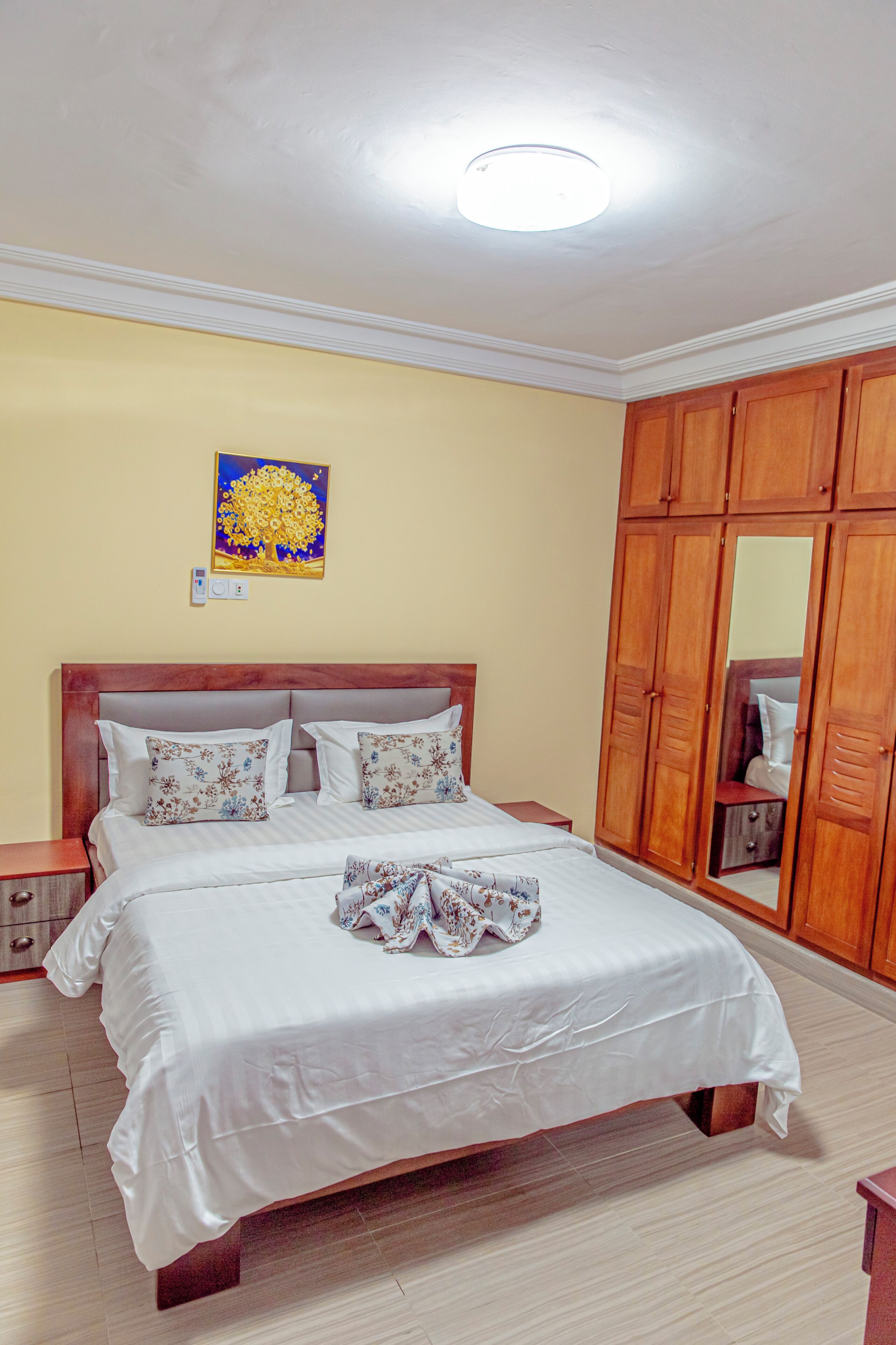 A bedroom with a wooden bed, a nightstand, a wardrobe, and a ceiling light.