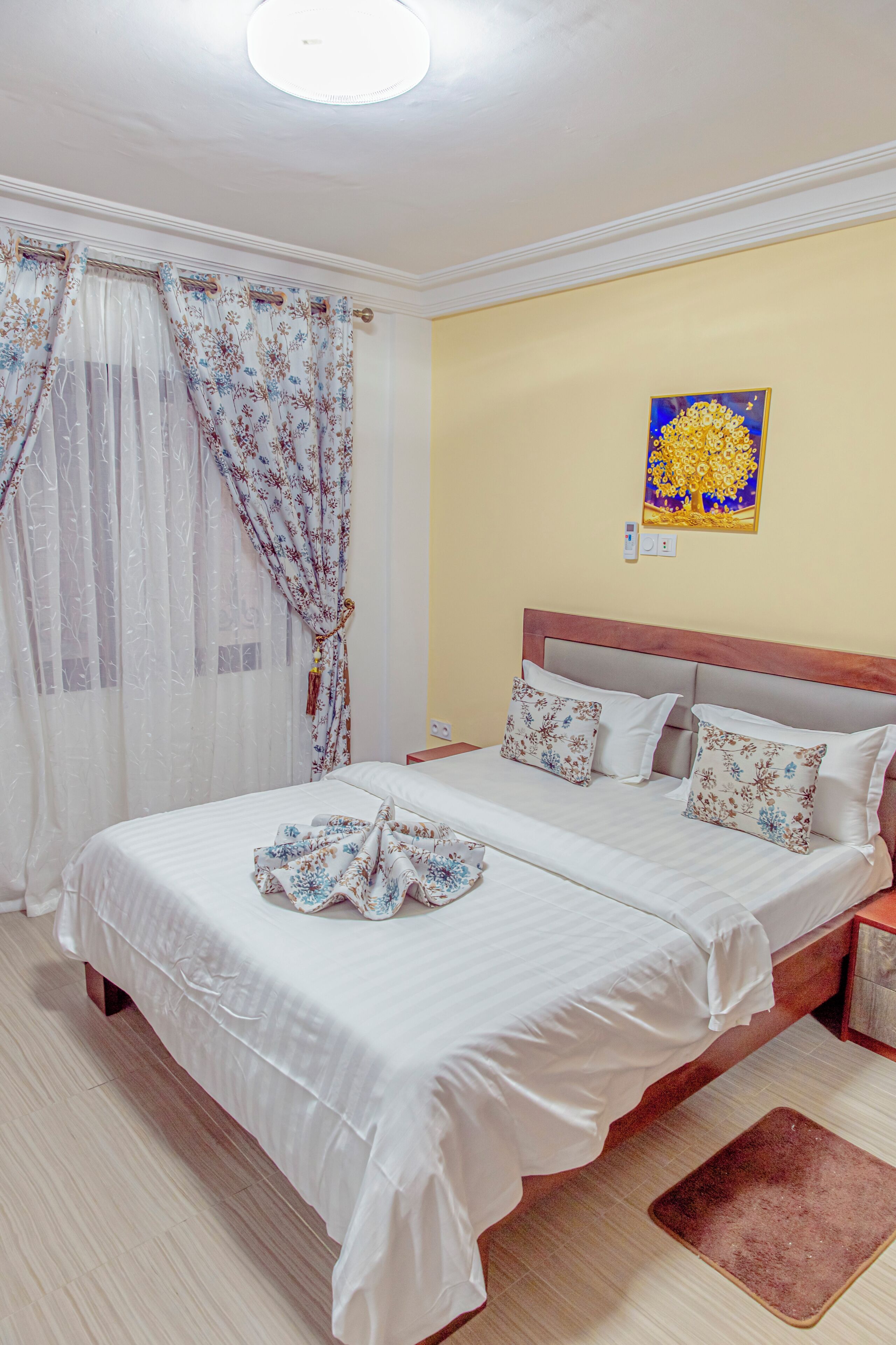 A double bed with white bedding, a wooden headboard, and two decorative pillows.