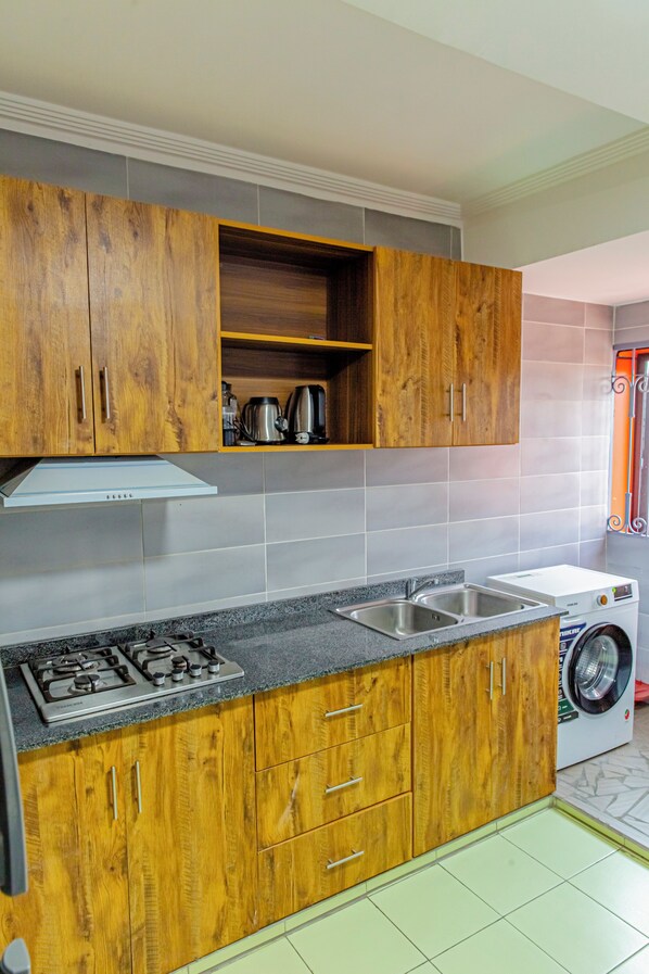 A kitchen with wooden cabinets, a gas stove, a built-in oven, a sink, and a washing machine.