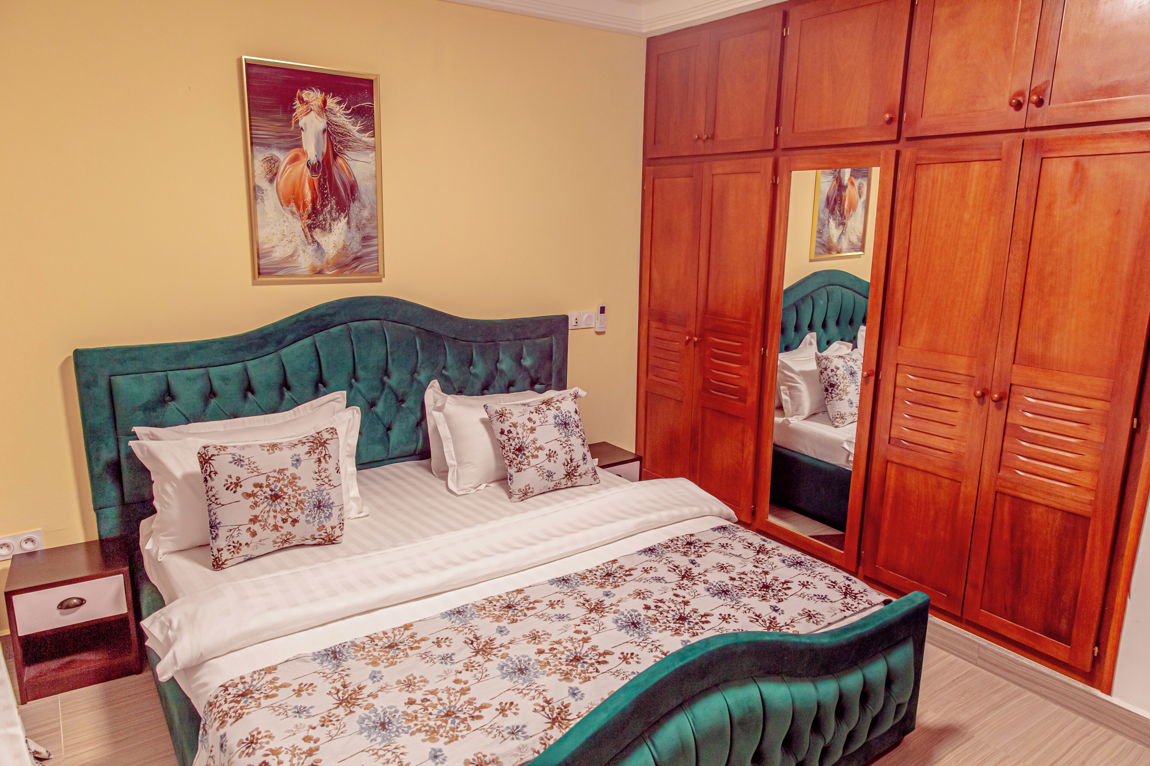 A bedroom with a bed, nightstands, a wardrobe, and a painting on the wall.