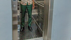 A person standing inside an elevator with a phone. - G&G Residency (Douala)