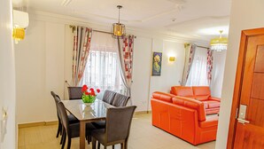 A dining area with a table and chairs, a sofa, and a chandelier. - G&G Residency (Douala)