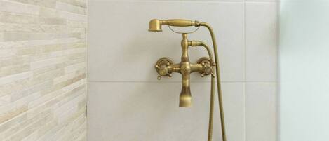 Un baño con un cabezal de ducha instalado en una pared con azulejos.