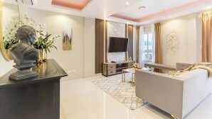 A modern living room with a sofa, TV, and decorative items. - Upscale 3 Br Apartment For Family Or Friends Stay (Santo Domingo)