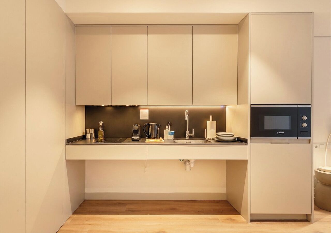 A modern kitchen with a built-in microwave, a coffee maker, and a sink.