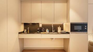 A modern kitchen with a built-in microwave, a coffee maker, and a sink.