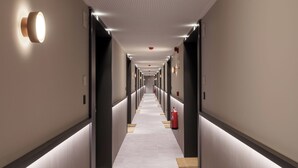 A long, narrow hotel corridor with a tiled floor, recessed lighting, and a fire extinguisher on the right wall. - Limehome Madrid Calle Hurtado de Mendoza (Madrid)