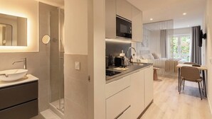 A modern kitchen with a built-in microwave, a sink, and a dining area with a table and chairs. - Limehome Madrid Calle Hurtado de Mendoza (Madrid)