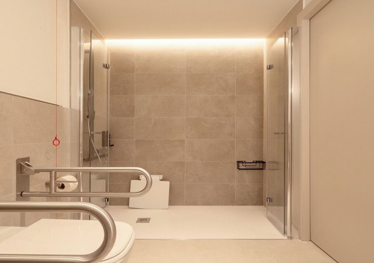 Un baño moderno con ducha, inodoro y barras de apoyo.