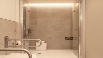 Un baño moderno con ducha, inodoro y barras de apoyo.