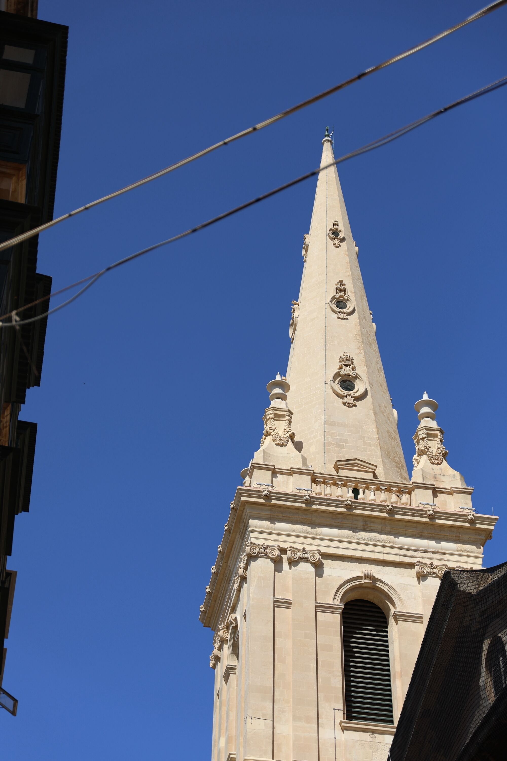 Un clocher d’église haut et richement décoré, surmonté d’une flèche pointue et orné d’éléments décoratifs.