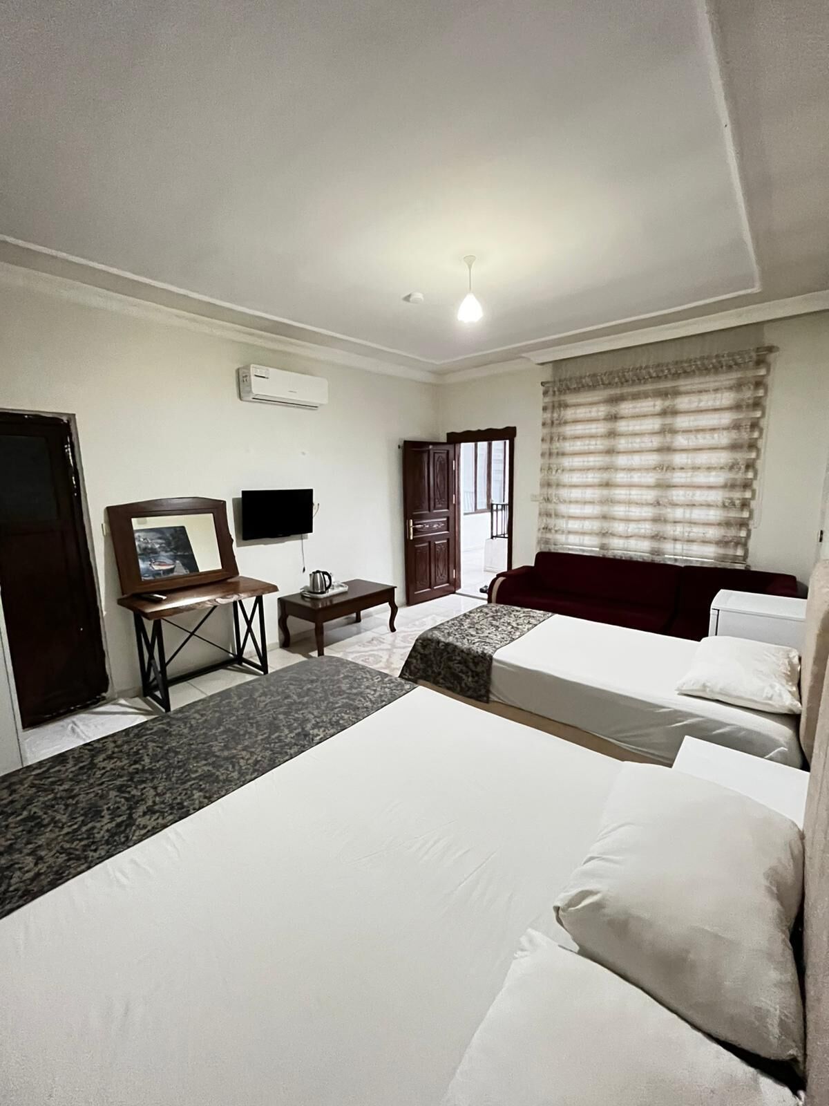 A hotel room with a bed, a desk, a chair, a TV, and a window with blinds.