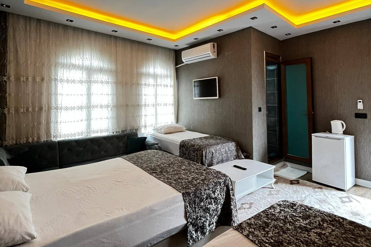 A modern hotel room with a bed, two bedside tables, a TV, and an air conditioning unit.