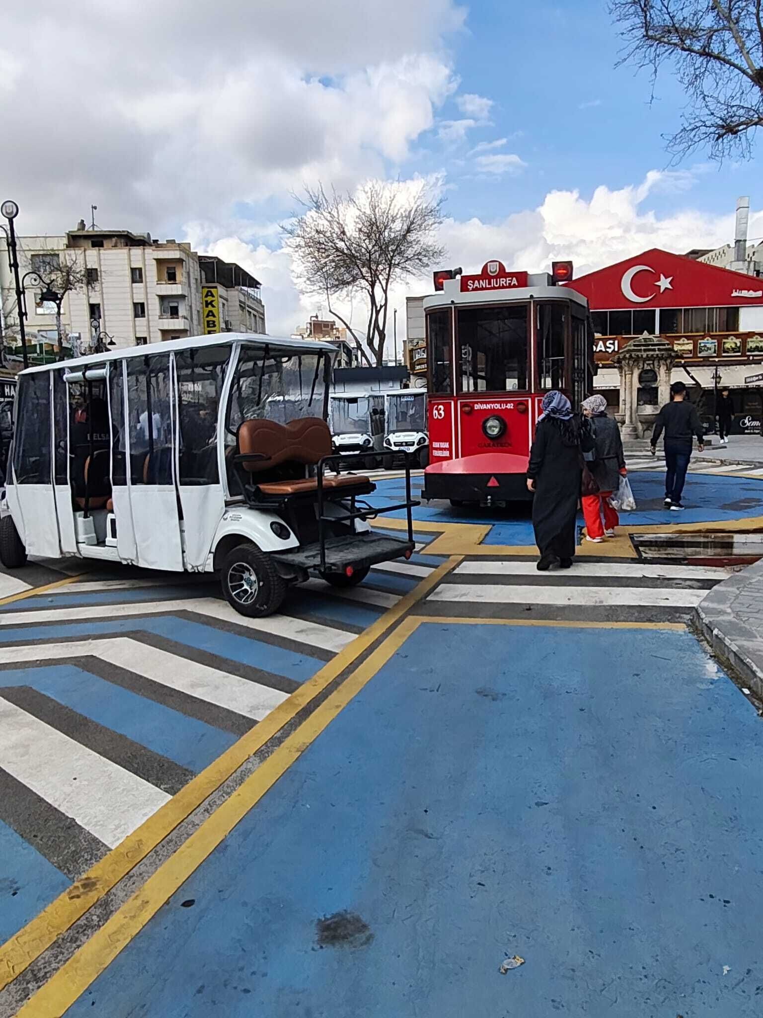 A tram at a crosswalk with people waiting.