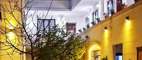 Un patio con piso de baldosas, un árbol y varias sillas.