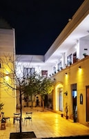 Un patio con piso de baldosas, un árbol y varias sillas.