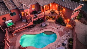 Una casa con piscina, mobiliario de exterior y una chimenea.