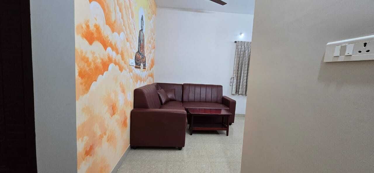 A living room with a brown leather sofa, a small table, and a wall with a mural.
