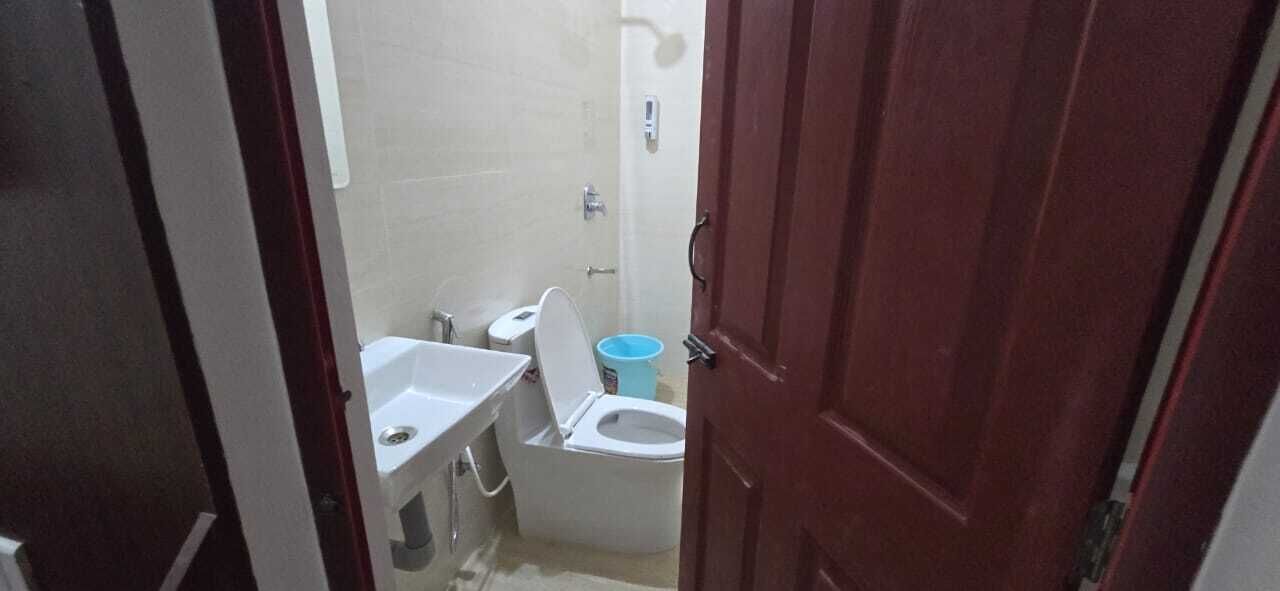Un baño pequeño con inodoro, lavamanos y un cubo azul.