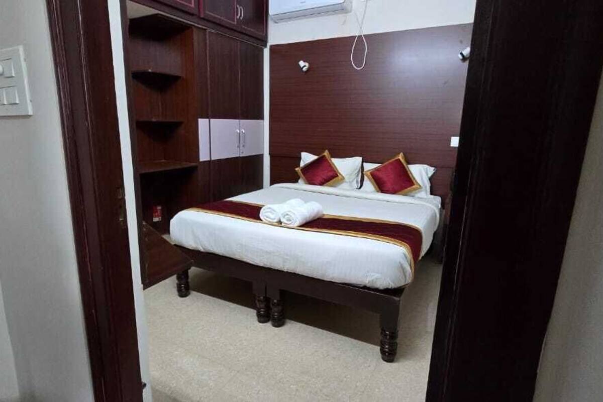 A neatly made bed with a white and red bedspread, a wooden headboard, and a small bedside table with a lamp.