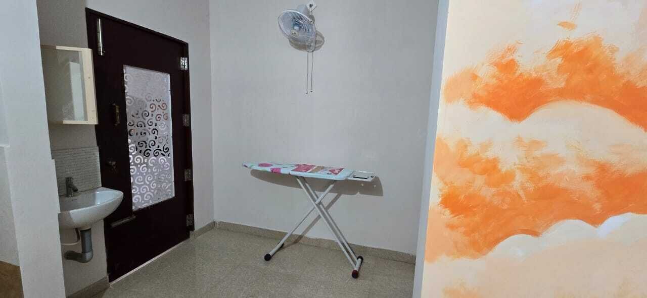 Un baño con lavabo, espejo, puerta con panel decorativo y tabla de planchar.