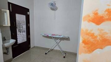 Un baño con lavabo, espejo, puerta con panel decorativo y tabla de planchar.