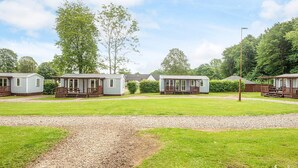 A row of mobile homes with wooden decks and a gravel path in the foreground. - 6 Person Holiday Park Home in Jelling (Jelling)