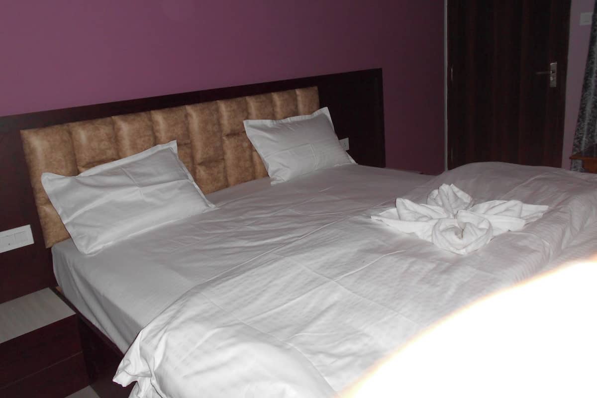 A neatly made bed with white linens and pillows, a tufted headboard, and a wooden nightstand.